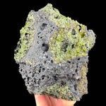 Green olivine and peridot crystals in a gray basalt rock matrix