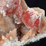 Close up of drusy Quartz and Stalactite Quartz crystals atop orange-red Calcite crystals